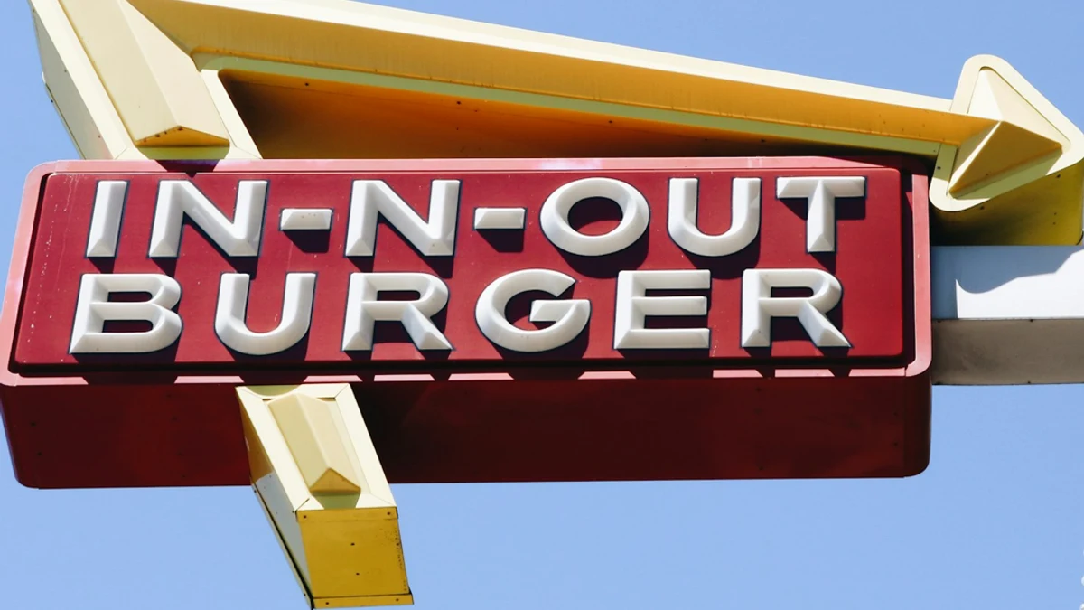 The red and yellow In-N-Out Burger roadside sign against a blue sky.