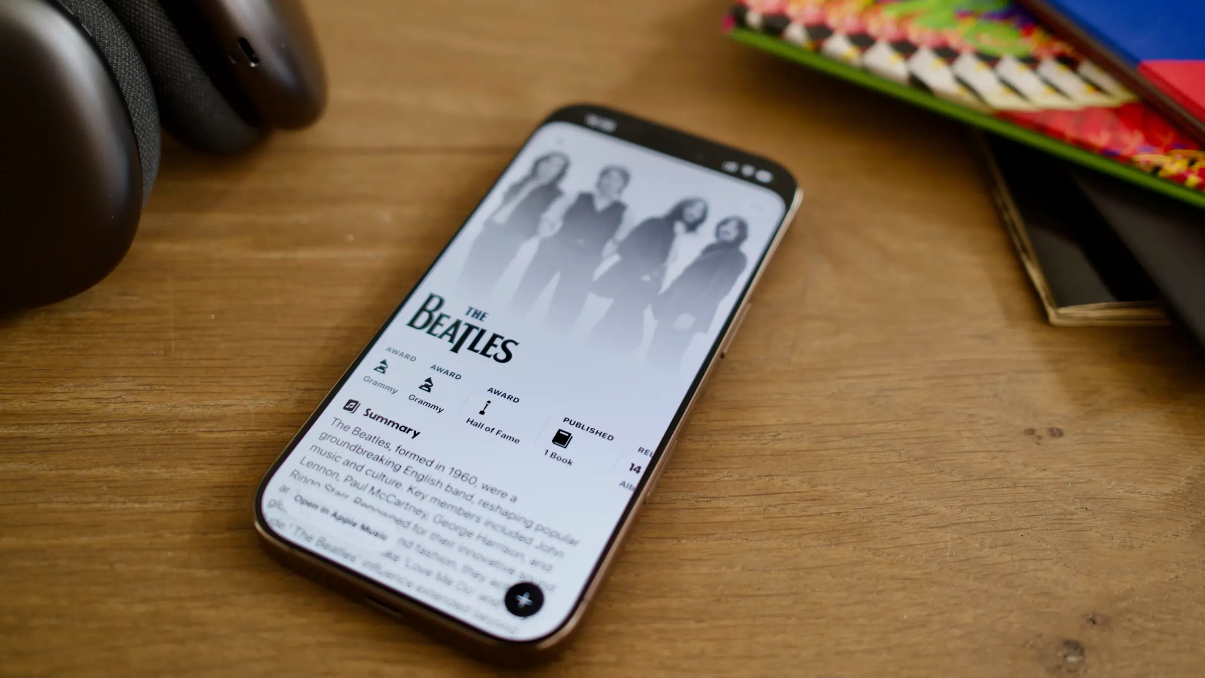 An image of an iPhone on a desk with the NowPlaying app open on The Beatles' artist page.